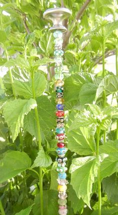 a glass beaded candle holder sitting in the middle of a garden filled with green leaves