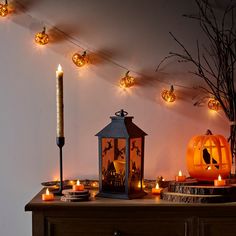 a table topped with candles and pumpkins next to a wall covered in halloween decorations