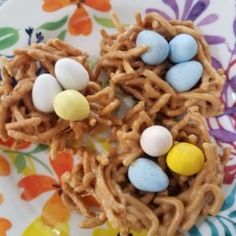 some kind of bird's nest with candy eggs in it on a flowered plate