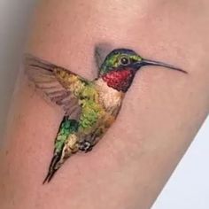 a colorful hummingbird tattoo on the right arm and leg, it is painted with multicolored paint