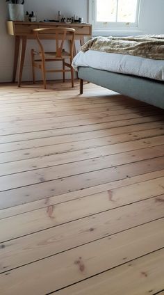 a bed sitting on top of a wooden floor next to a desk and chair in a bedroom