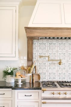 a stove top oven sitting inside of a kitchen next to white cabinets and counter tops