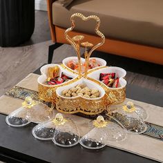 an assortment of food is displayed on a coffee table with wine glasses and spoons