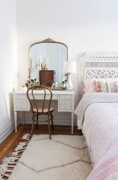 a bedroom with a bed, desk and mirror on the wall next to each other