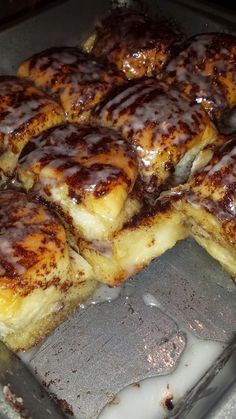 cinnamon rolls with icing sitting on top of a pan