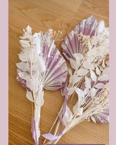 two dried flowers sitting on top of a wooden table next to a purple and white ribbon