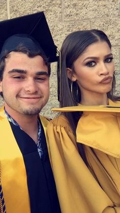 a man and woman in graduation gowns posing for the camera