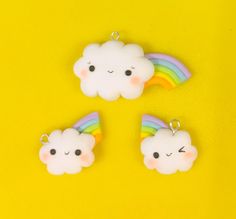 three little clouds with rainbows on them sitting next to each other in front of a yellow background