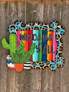 a wooden sign that says welcome y'all with a cactus and cacti