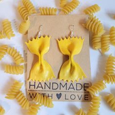 two yellow flower shaped earrings sitting on top of pasta