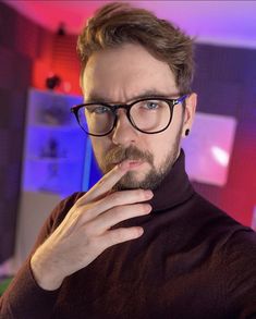 a man with glasses and a beard is posing for the camera while wearing a turtle neck sweater