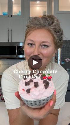 a woman holding up a cupcake with pink frosting and chocolate decorations on it