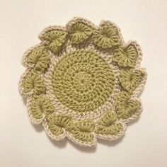 a crocheted doily with green leaves on the top and bottom, sitting on a white surface