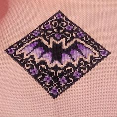 a close up of a cross - stitch pattern on a pink shirt with black and purple details