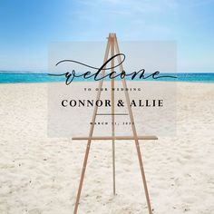 an easel sitting on top of a beach with the words welcome to our wedding