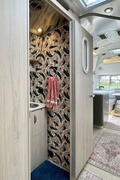 the inside of a camper with an open door and colorful wallpaper on it