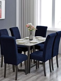 a dining room table with blue chairs and a vase on the table in front of it