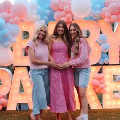 three women standing next to each other in front of balloons and letters that say happy birthday