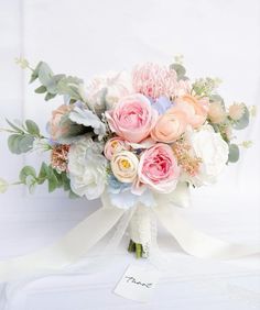 a bridal bouquet with pink, peach and white flowers on a lace table cloth