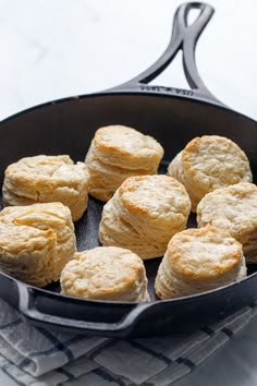 biscuits are cooking in a skillet on top of a towel next to a fork