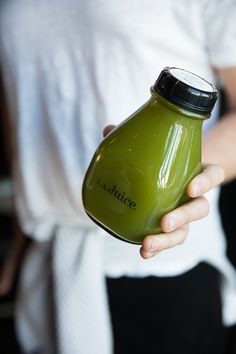 a person holding a green bottle in their hand