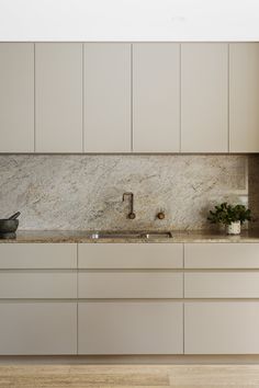 a kitchen with white cabinets and marble counter tops