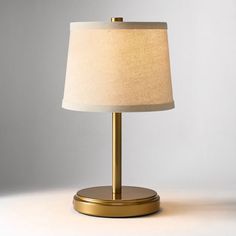 a lamp that is on top of a table with a white shade over the base