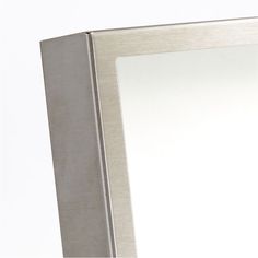 a silver framed mirror sitting on top of a white wall