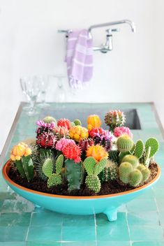 a bowl filled with lots of colorful flowers on top of a counter next to a sink