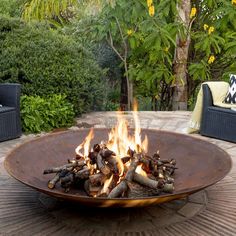 a fire pit sitting on top of a wooden table next to a lush green forest