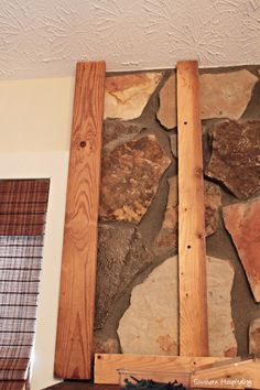 a stone wall with some wood in front of it and a window frame on the other side