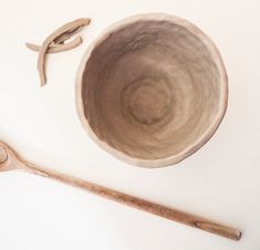 two wooden spoons and a ceramic bowl on a white surface with a wood spoon