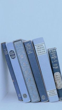 four books are lined up in a row on a white surface, one is blue and the other is gray