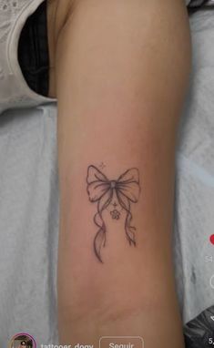 a woman's arm with a bow tattoo on it