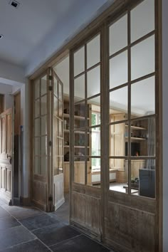 an open door leading to a kitchen with lots of wood and glass on the doors