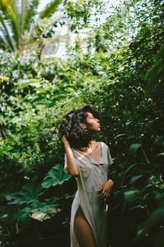 a woman standing in the middle of some bushes