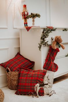 christmas stockings and teddy bears are on the floor in front of a white chest with decorations