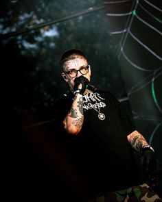 a man with tattoos on his arm holding a microphone