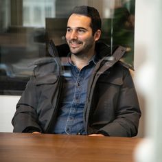 a man sitting at a table with his hands on his hips and looking off into the distance