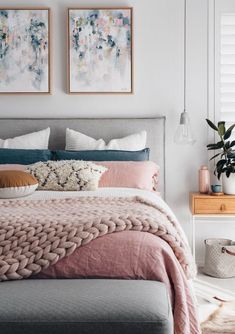 a bedroom with two paintings above the bed and pillows on the headboard in front of it