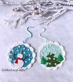 two crocheted christmas ornaments hanging on a white tablecloth with snowflakes