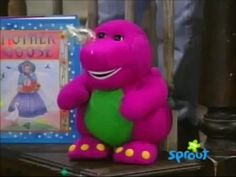 a purple stuffed animal sitting on top of a table next to a children's book