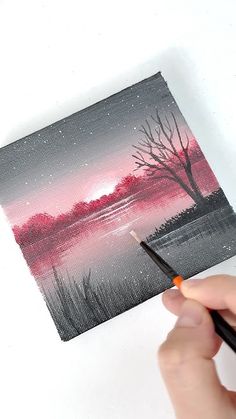 someone is holding a paintbrush and painting a landscape with red, pink and black colors