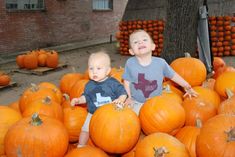 two young boys sitting in a pile of pumpkins