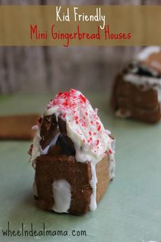 a small gingerbread house with white frosting and red sprinkles on top