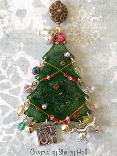 a green christmas tree ornament hanging on a white wall with ornaments around it