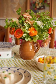 a vase filled with flowers sitting on top of a table next to plates and bowls