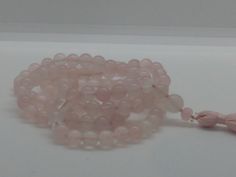 This beautiful mala is ideal for working with anything related to love and to the heart. It is made of 108 8mm Rose Quartz beads, a Rose Quartz guru bead, and a handmade pink tassel. Rose Quartz is one of the signature stone of love. It is especially helpful for learning to love the self, but it's also a  wonderful stone for love relationships of all kinds, and also for attracting more love into your life. It's soothing for broken hearts because it helps with caring for and nurturing the self, a Rose Quartz 108 Beads Jewelry For Meditation, Hand Wrapped Round Beads Mala For Meditation, Hand Wrapped Mala With Round Beads For Meditation, Hand Wrapped Mala For Meditation, Spiritual Rose Quartz Beaded Bracelets For Meditation, Spiritual Rose Quartz Beaded Bracelet For Meditation, Spiritual Rose Quartz Beaded Necklaces, Spiritual Rosary With Round Beads For Meditation, Spiritual Rosary For Meditation With Round Beads