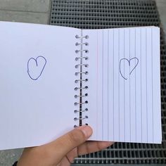 someone is holding up a notebook with two hearts drawn on the pages and one has a pencil in it