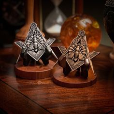 two small metal items sitting on top of a wooden table next to an orange vase